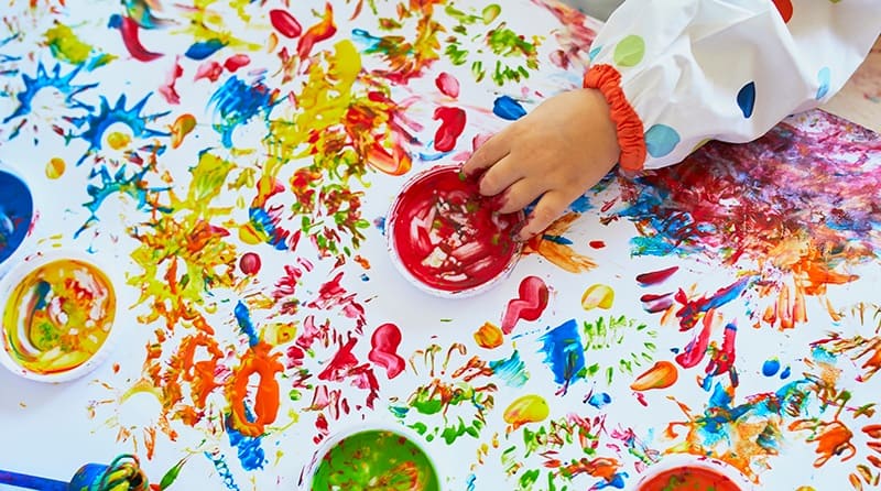 A child's hand getting involved in messy play activities.