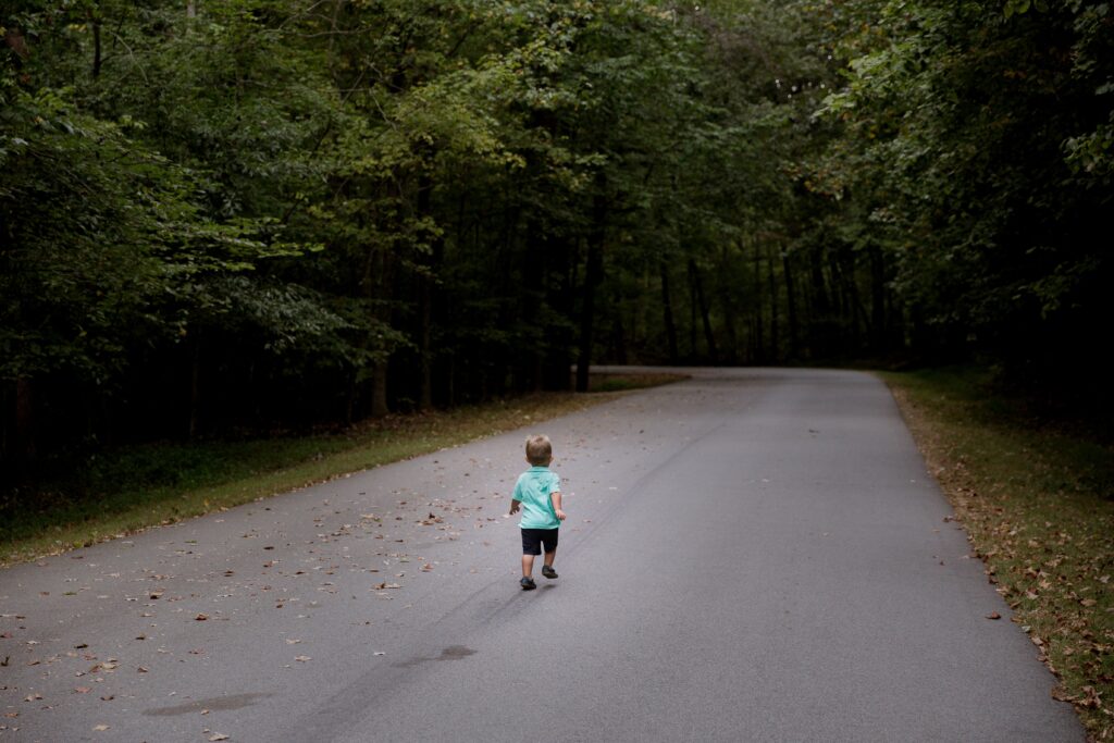A little boy is walking down the middle of a road. Gentle parenting sets boundaries.