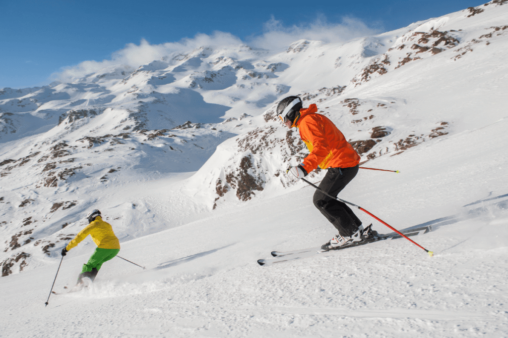 Two people skiing downhill. Source: Canva