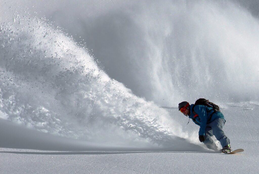 Someone riding powder on their snowboard. Photo by Johannes Waibel on Unsplash