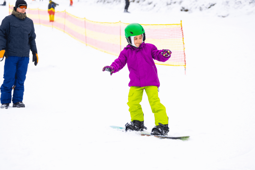 A young child learning to snowboard. Source: Canva