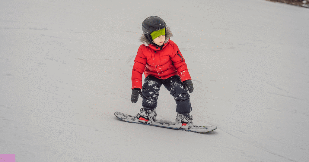 A young child snowboarding on snow. Source: Canva