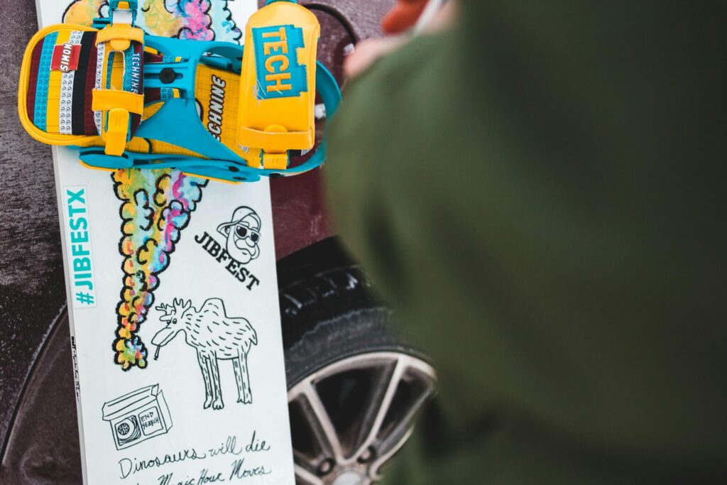 A kid's snowboard leaning against a trunk. Photo by Erik Mclean on Unsplash