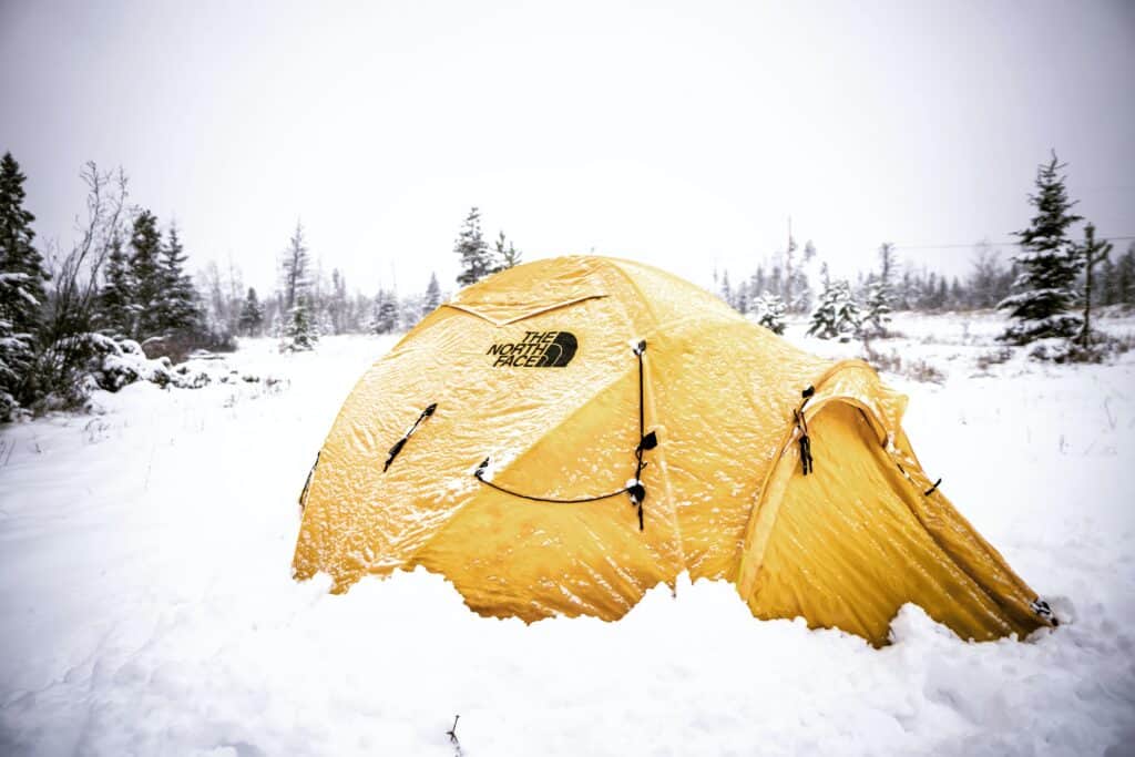 A yellow tent in the snow. Photo by Dylan Drego on Unsplash