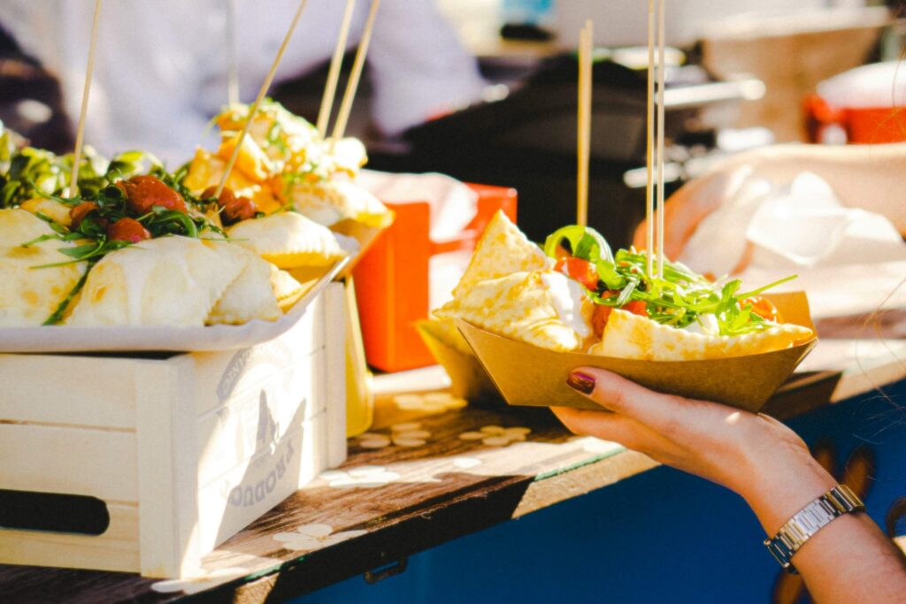 Someone getting a wrap with a salad in a brown box at a festival. Photo by frogses production on Unsplash