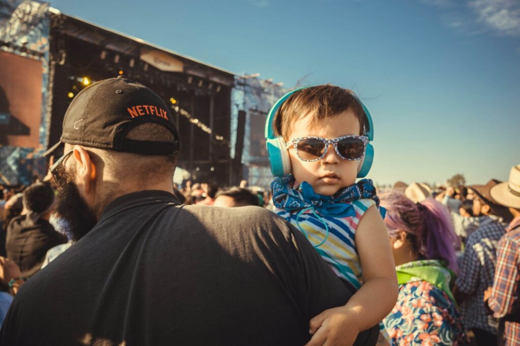 A young child wearing ear defenders at a music festival. Photo by Charlie Solorzano on Unsplash
