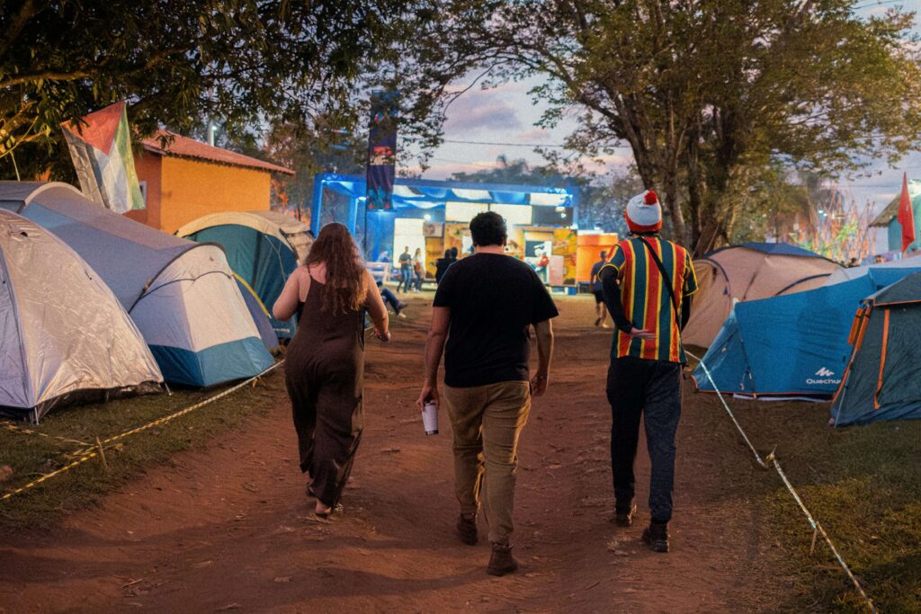 Three people walking past tents at a festival. Photo by Kenji Katahira on Unsplash