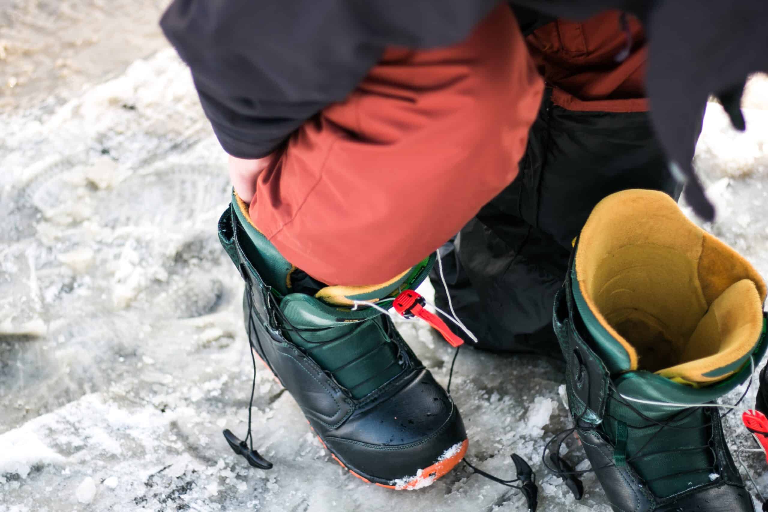 Someone putting on snowboard boots. Photo by Joshua Reddekopp on Unsplash