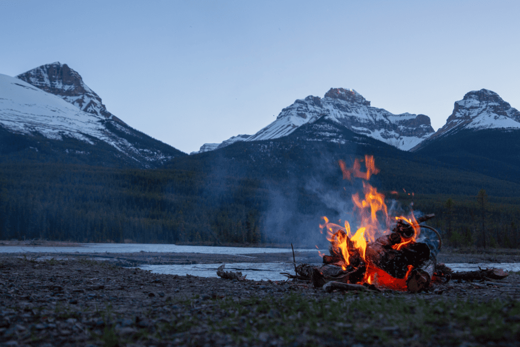 A camp fire with mountains in the background. Photo by Courtnie Tosana on Unsplash