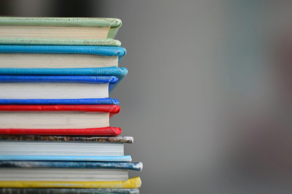 A stack of books. Solo camping entertainment. Photo by Kimberly Farmer on Unsplash
