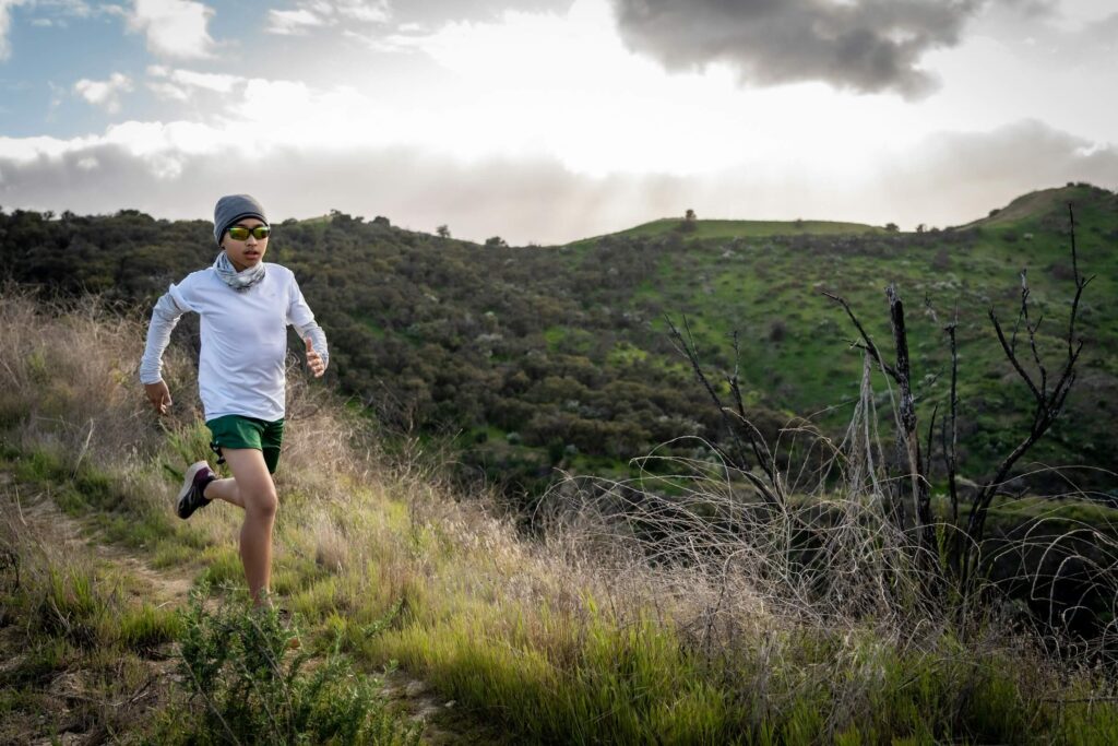 A trail runner along a hilly path wearing trail running gear. Photo by Steve Wiesner on Unsplash