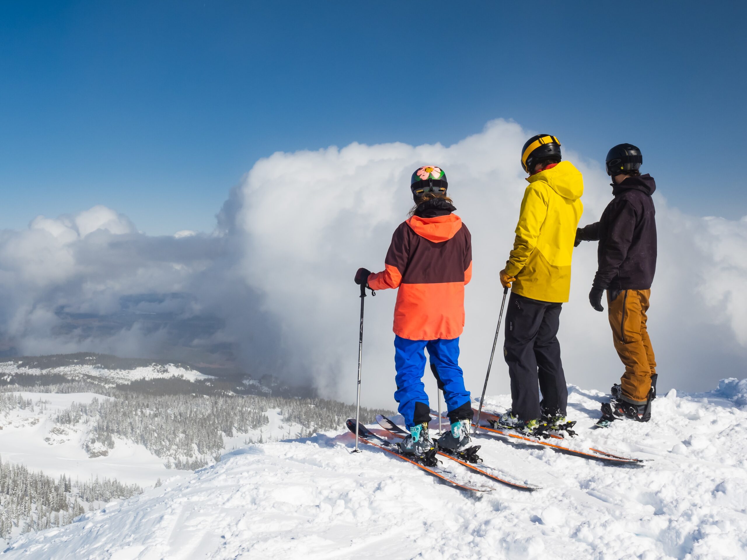 Three skiers looking down the mountain. Best ski jackets. Photo by Greg Rosenke on Unsplash