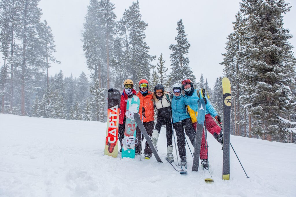 A group photo of friends skiing and snowboarding. Photo by Laura Corredor on Unsplash