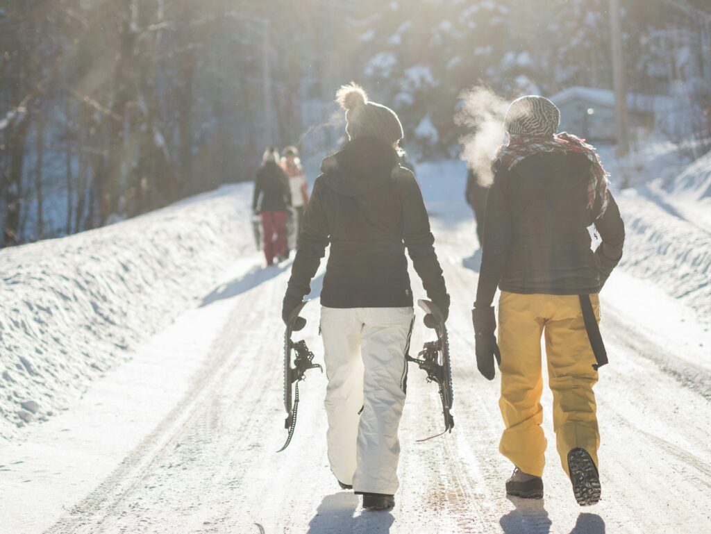 Walking along holding skis while wearing ski jackets. Photo by Alain Wong on Unsplash