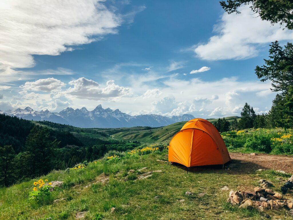 An orange tent overlooking the mountains. Photo by Jesse Gardner on Unsplash