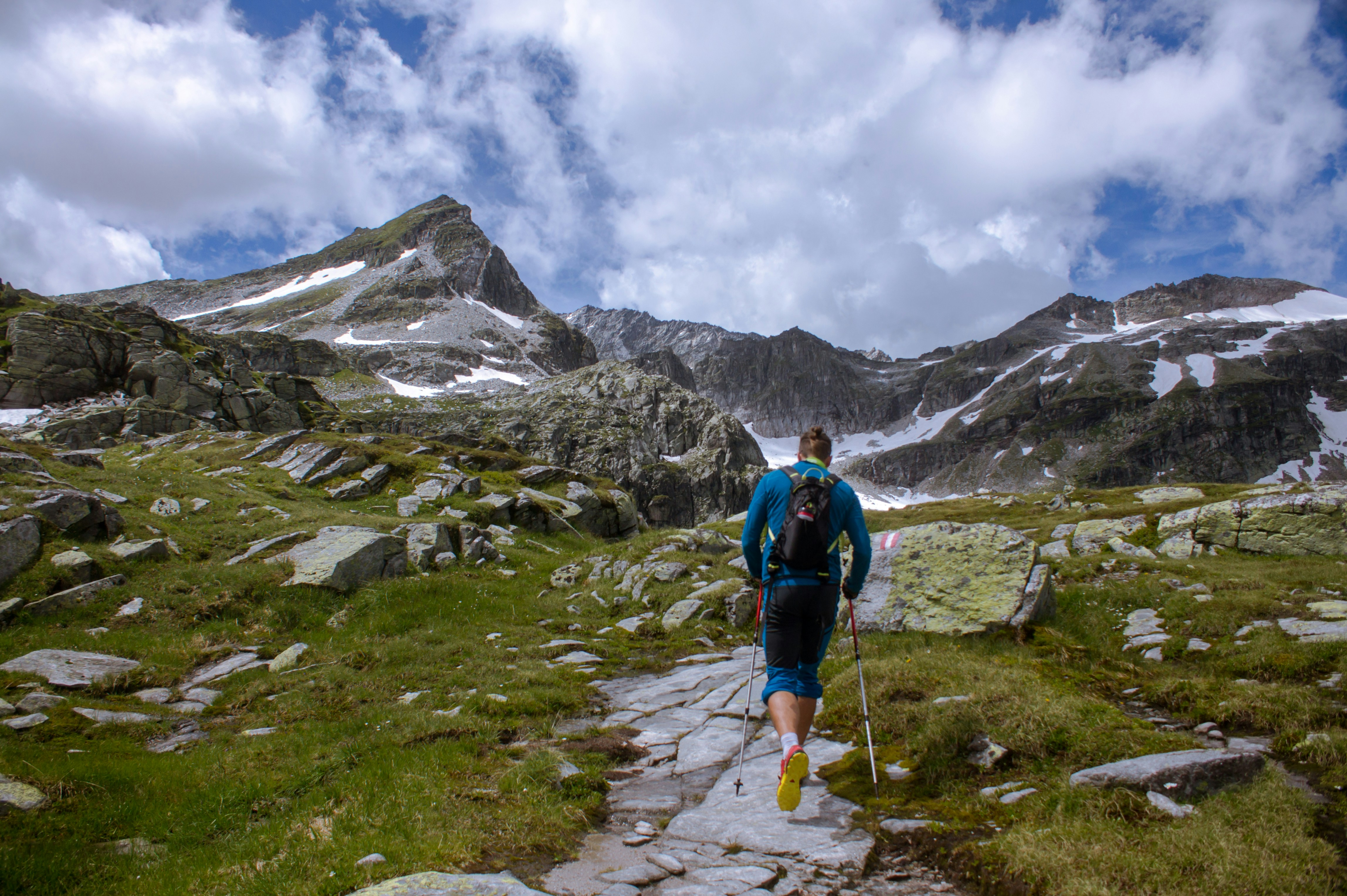 Person hiking with walking poles on uneven terrain with the mountains in front of them. Photo by Jan-Niclas Aberle on Unsplash