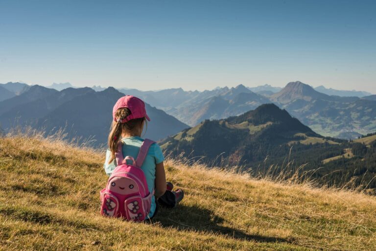 A young girl sitting overlooking a mountain range. Photo by S&B Vonlanthen on Unsplash