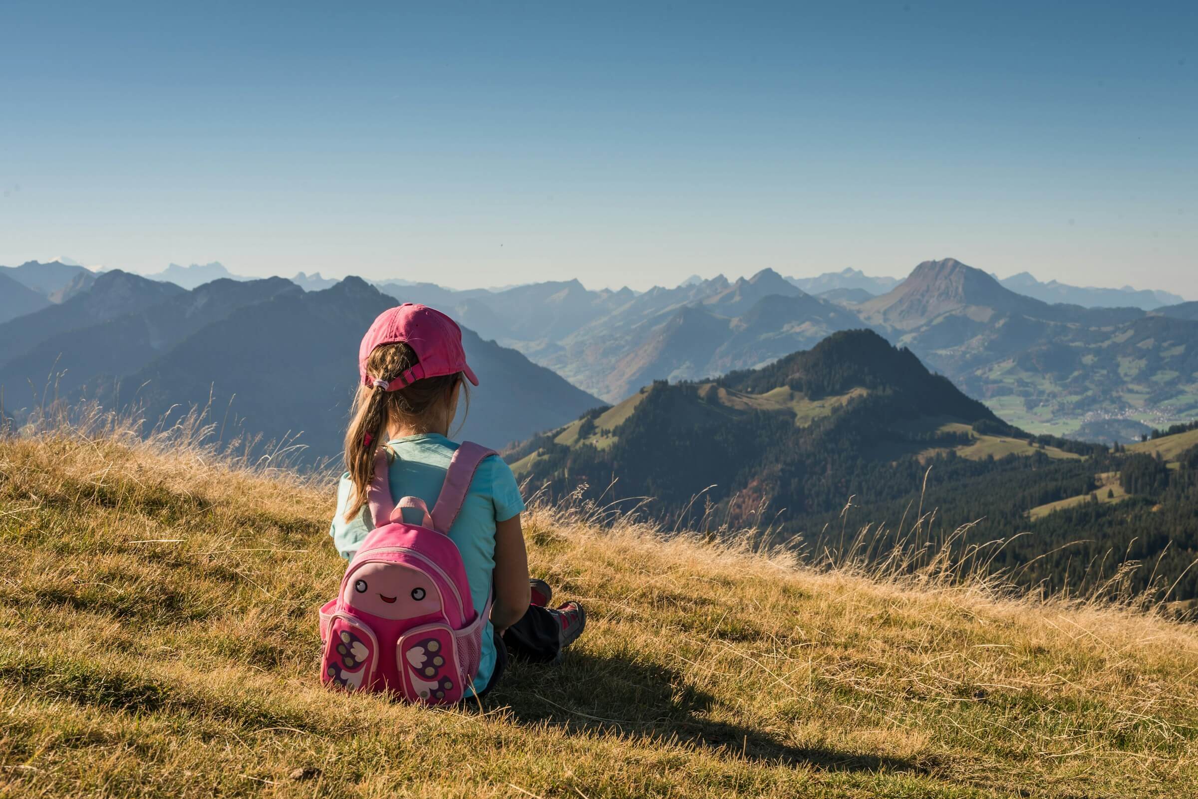 A young girl sitting overlooking a mountain range. Photo by S&B Vonlanthen on Unsplash