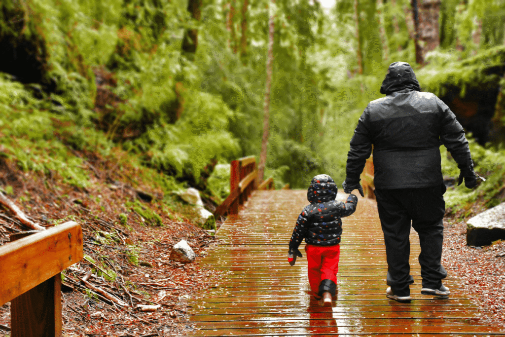 A father and son walking through the forest in the rain. Source: Canva