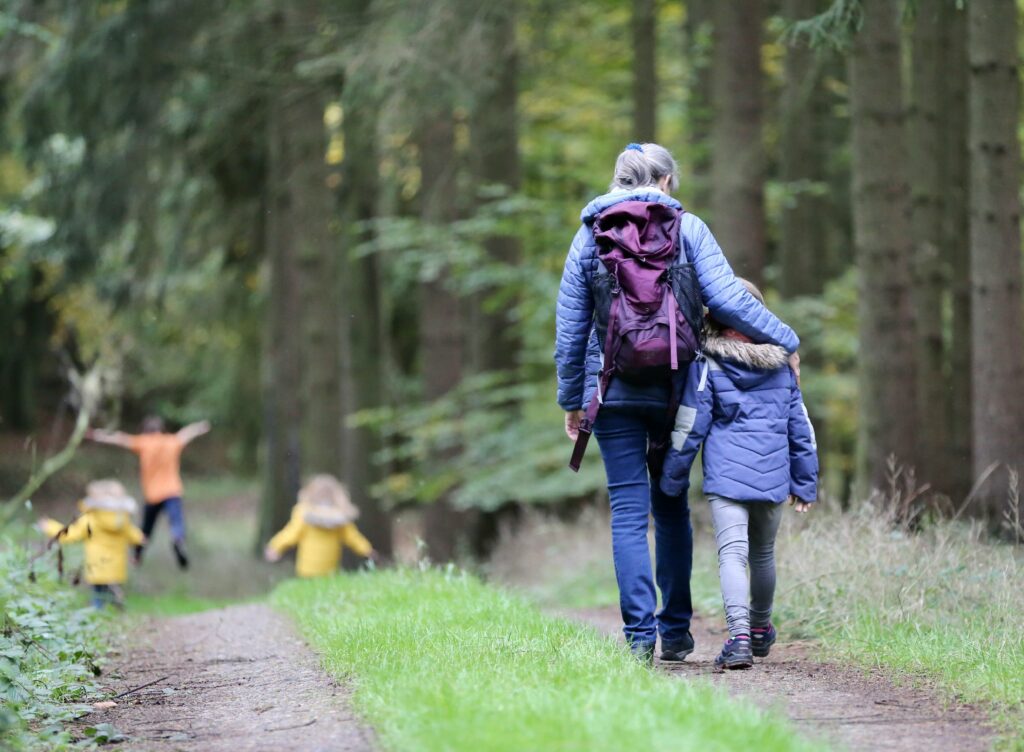 A family enjoying a walk through the woods, wearing warm jackets. Photo by Juliane Liebermann on Unsplash