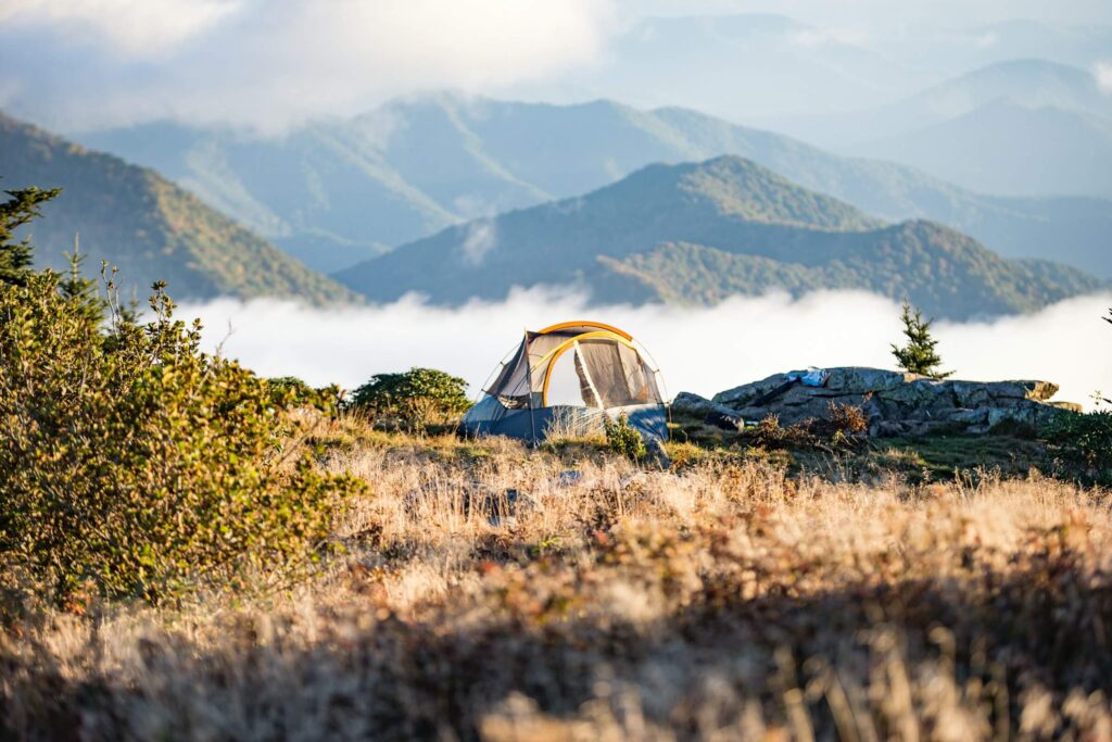 A tent overlooking the mountains with low level clouds. Photo by Christopher Jolly on Unsplash