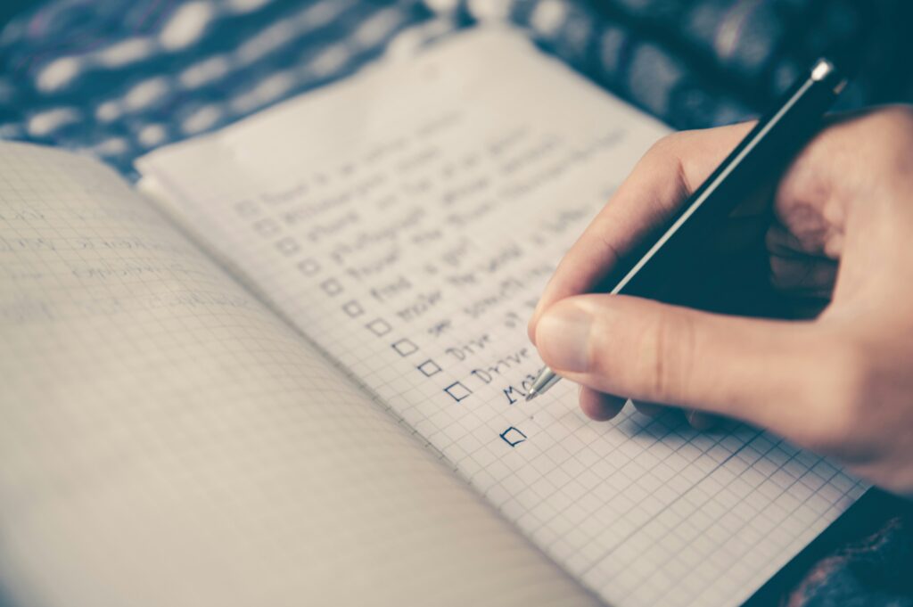 Someone writing a checklist. Autumn camping checklist. Photo by Glenn Carstens-Peters on Unsplash