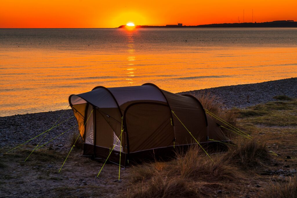 A tent near water at sunset. Autumn camping destinations in the UK. Photo by martin bennie on Unsplash