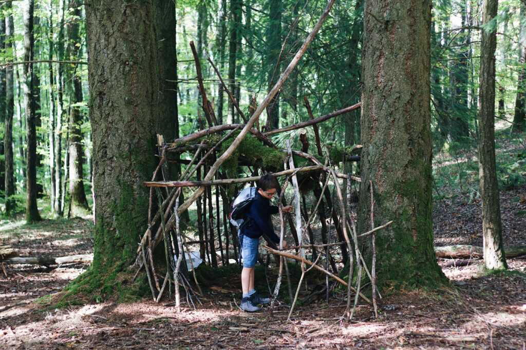 A young child building a den. Photo by Maël BALLAND on Unsplash