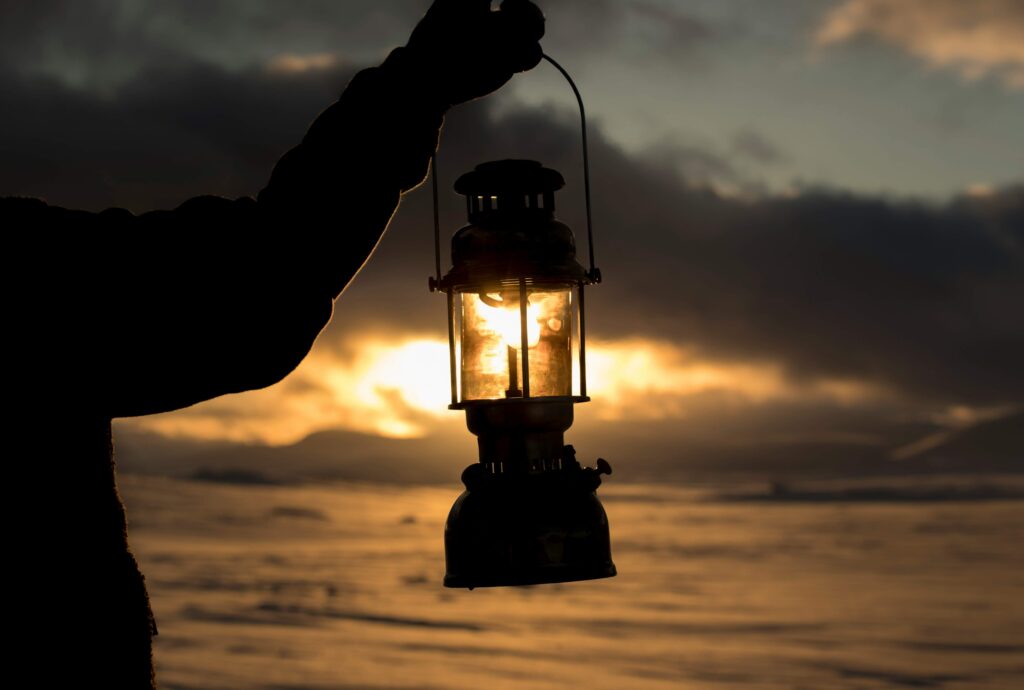 Someone holding a lantern up with dark clouds in the background. Photo by Thomas Lipke on Unsplash