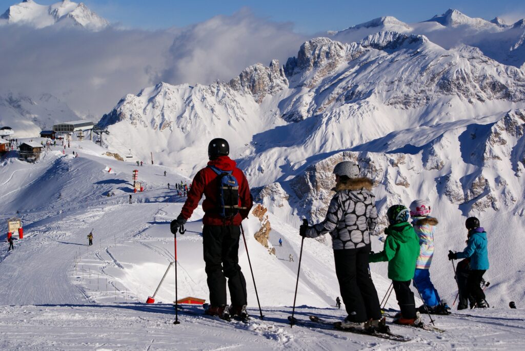 A family skiing looking at the view at the top of a mountain. Photo by Piotr Figlarz on Unsplash
