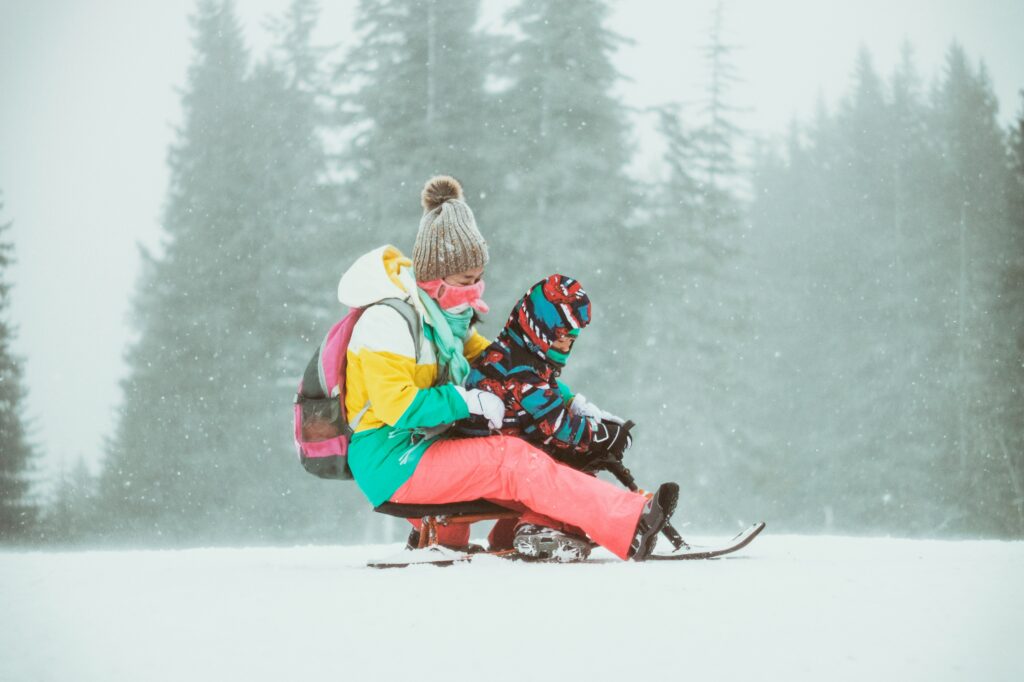 A woman and young child sledging on the snow. Photo by Dimitar Krastev on Unsplash