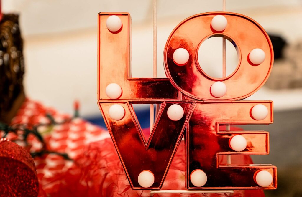 An LOVE sign that's red with white balls in each of the letters. Valentine's Day gifts for campers and hikers. Photo by Jesse Goll on Unsplash