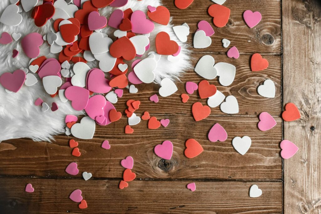 Different coloured Valentine hearts on a wooden surface and a white fluffy rug. Photo by Element5 Digital on Unsplash
