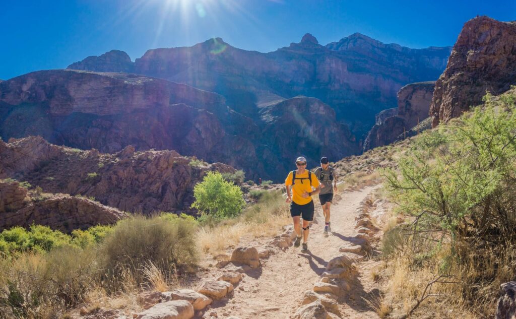 Two men running along a mountain trail. Photo by Brian Erickson on Unsplash