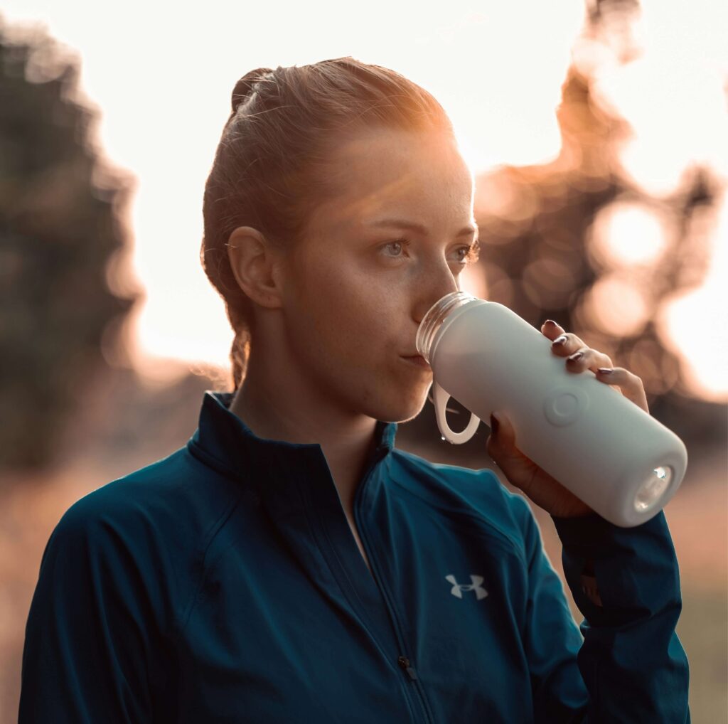 A female runner drinking from a water bottle. Photo by Bluewater Sweden on Unsplash