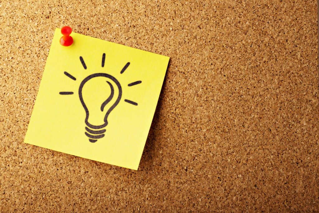 A yellow sticky note with a picture of a lightbulb on it, stuck to a pin board. Spring camping checklist. Photo by AbsolutVision on Unsplash