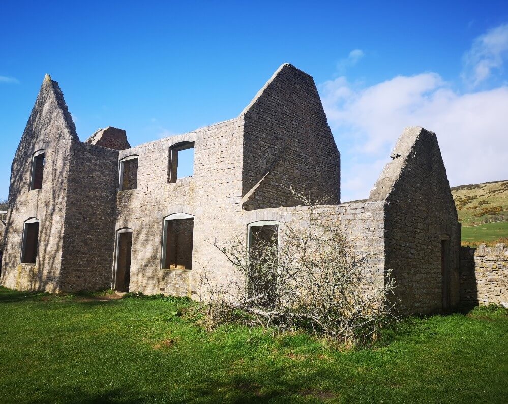 The Gardener's Cottage with Mrs Anne Curtis in Tyneham Village. Just the structure of the building remains. Tyneham Village and Worbarrow Bay. Source: Rebecca Campbell Ltd