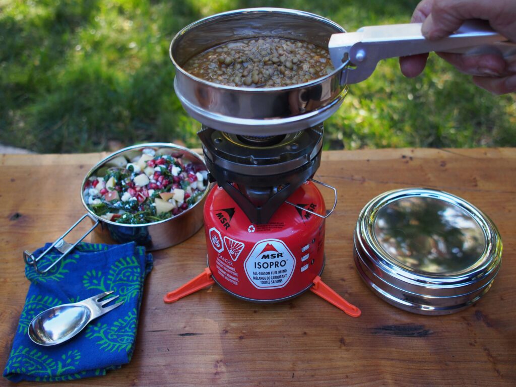 Someone cooking food over a camping stove outside. Photo by Sandra Harris on Unsplash