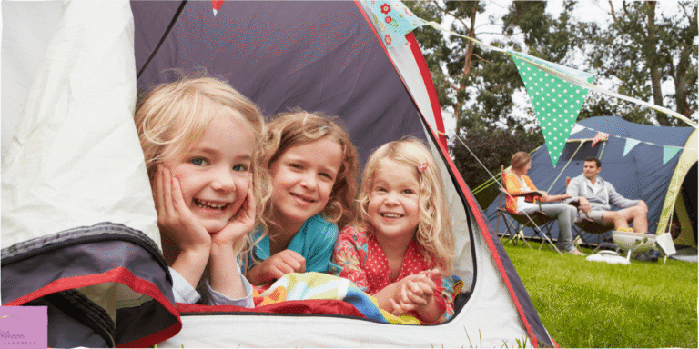 Children sticking their heads out of a tent, camping outside. Family camping in summer. Source: Canva