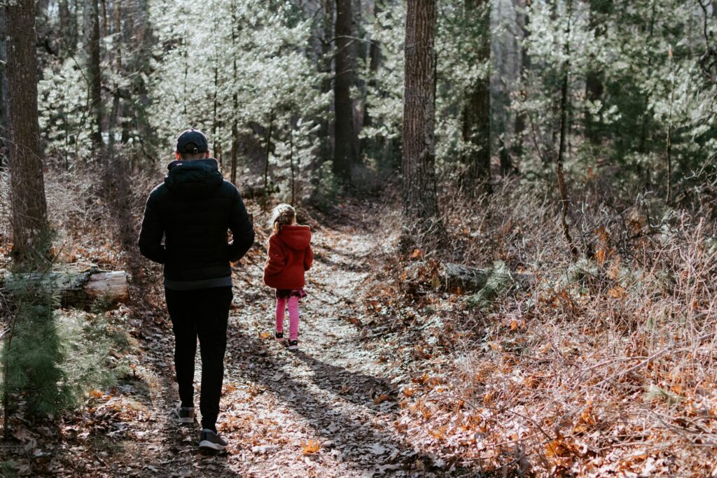 Walking through the woods on a summer nature walk. Summer camping activities for families. Photo by Kelly Sikkema on Unsplash