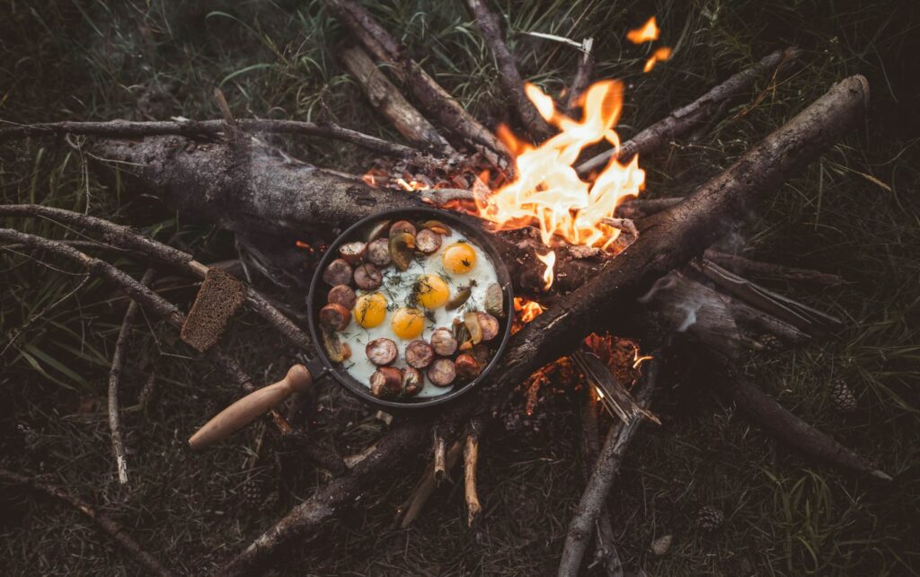 Cooking eggs and mushrooms over a camp fire. Photo by Vadim Sadovski on Unsplash