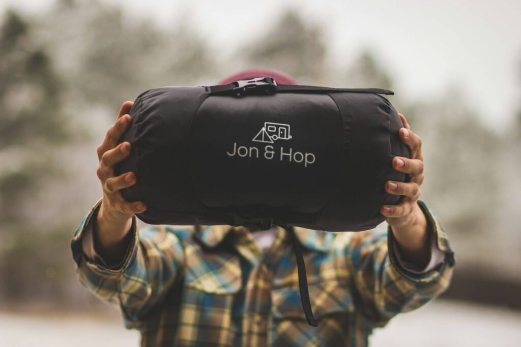 Someone holding a sleeping bag between their hands. Best Sleeping Bag for Summer Camping with Kids. Photo by Spring Fed Images on Unsplash