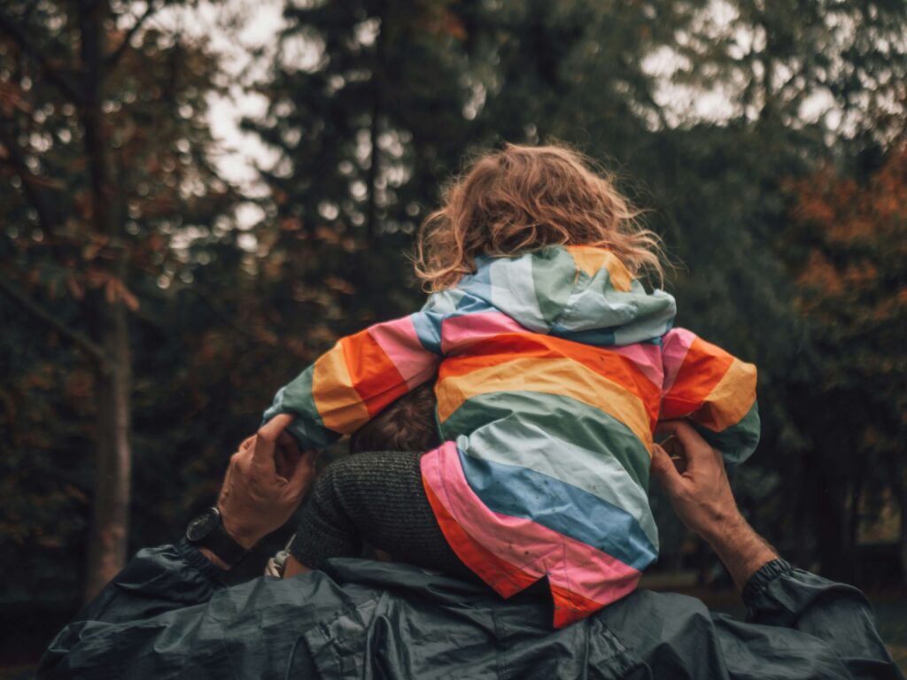 A little child going on the back of someone's shoulders. Keeping kids motivated on hikes. Photo by Moodthy Alghorairi on Unsplash