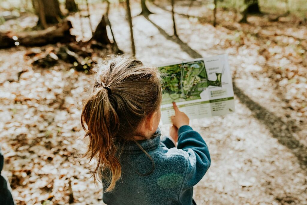 A young girl holding a map and pointing to a section on the trail. Photo by Sandra Seitamaa on Unsplash