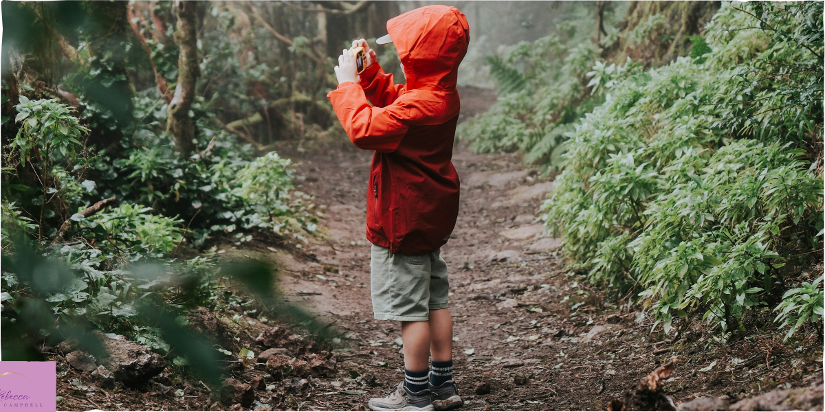 A little boy taking a photo along a forest path. Photo by Nenad Radojčić on Unsplash